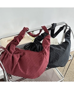 Detail view of crescent canvas bags with plaid patterns and pleated texture design