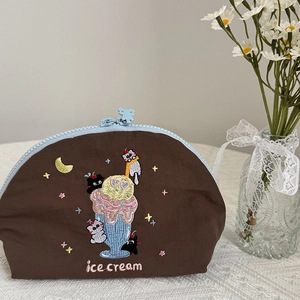 Dettaglio ricamo gatto e gelato su borsa cosmetica marrone con zip a forma di orsetto