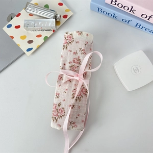 Floral makeup brush roll bag tied with a pink satin ribbon and elegant pattern