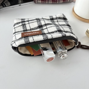 Detail of checkered canvas pouch with zipper and leather tag showing lipstick storage