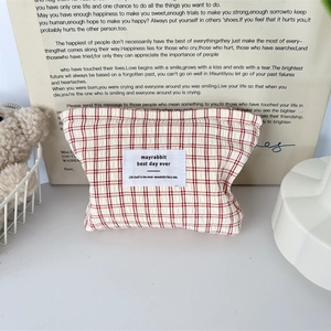 Détail de la trousse à maquillage en tissu à carreaux rouges et blancs avec étiquette