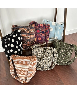 Detailed view of various plush leopard and pattern bucket bags on a wooden shelf