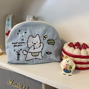 Dettaglio trousse in cotone azzurro con ricamo di cane e chiusura con cerniera