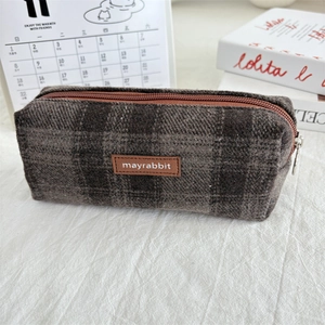 Detail of vintage brown plaid tweed pencil case with leather logo and metal zipper