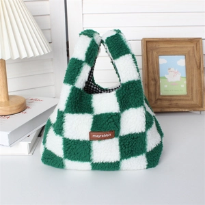 Detail of green and white checkered plush handbag with leather logo on a cozy table