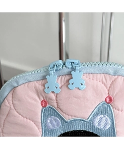 Detail of pink quilted cosmetic bag with blue zippers and cute bear-shaped pullers