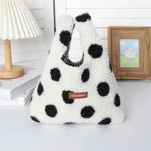 Detailed view of plush lamb wool handbag with polka dots and brown logo tag