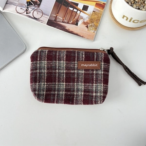 Flat lay of vintage plaid coin purse with top zipper and woven cord on white desk