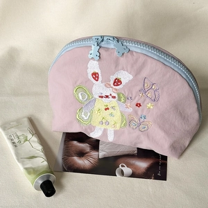 Dettaglio della borsa ricamata rosa con motivo a coniglio e zip con orsetto blu carina