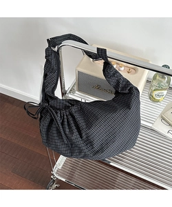 Detail of checkered canvas bag featuring a side drawstring bow and zip closure detail