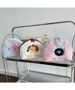 Detailed view of quilted makeup bags with cute animal embroidery on a metal shelf
