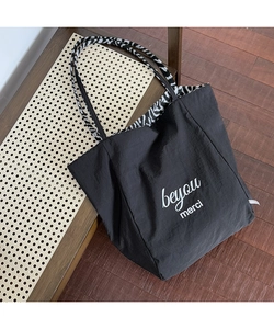 Detail of black tote bag with zebra print lining and beyou merci text on front