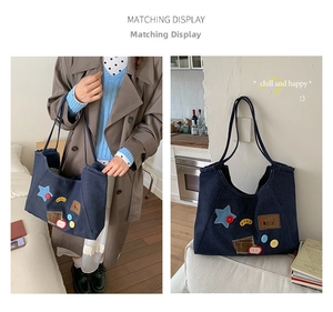 Detail of blue denim tote bag featuring vintage DIY patches and slim double straps