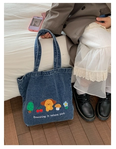 Detail of blue denim tote bag with cute cartoon puppy embroidery and shoulder strap