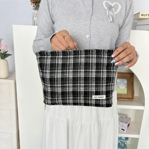 Close-up of black and white checkered canvas pouch with May Rabbit brand label