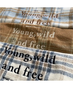 Close-up of wool plaid tote bag texture featuring embroidered inspirational text