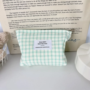 Détail de la trousse à maquillage en seersucker à carreaux vert et blanc avec étiquette