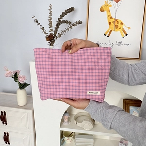 Detail van roze geruite toilettas met stoffen merklabel en soepele ritssluiting
