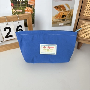 Blue nylon cosmetic bag for lipstick on a desk with decor, shown in a lifestyle setting