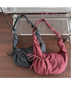 Detail of plaid canvas crescent bags with adjustable straps and drawstring bows