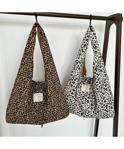 Close-up of two leopard print corduroy tote bags with white woven labels and sturdy handles
