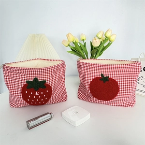Detail of red checkered cosmetic pouches with cute strawberry and tomato embroidery