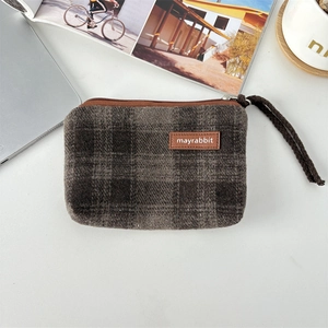 Detail of vintage plaid coin purse with leather tag on office desk lifestyle scene