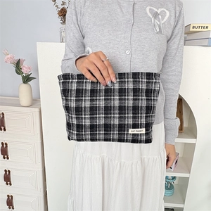 Detail of high-quality plaid canvas pouch showing checkered texture and brand label