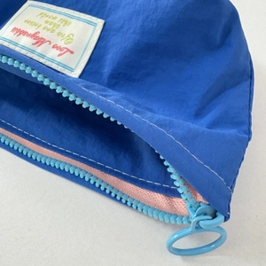 Close-up of royal blue nylon makeup bag with pink lining and large ring zipper detail