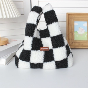 Detail view of plush black and white checkerboard tote bag with brown leather label logo