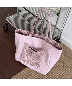 Detail view of the pink leopard print pocket and thick canvas texture on the tote bag