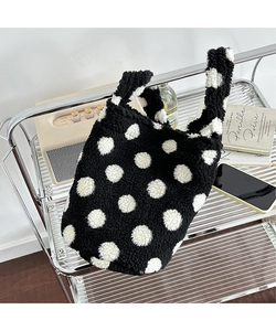 Detail of plush polka dot tote bag with soft faux lamb wool texture on metal shelf