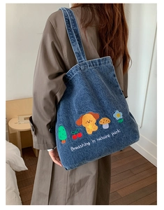 Detail of blue denim tote bag with cute cartoon dog and cherry embroidery accents