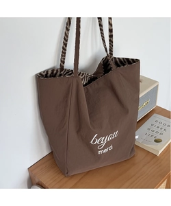 Close-up of brown tote bag featuring white text and zebra print lining on a wooden cabinet