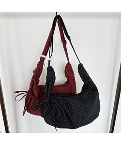 Detail of checkered canvas crossbody bag with side drawstring bows and adjustable strap