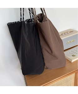 Detail of black and brown tote bags with striped straps in a cozy indoor setting