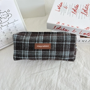 Detail of vintage plaid wool pencil case with premium leather logo tag and zip closure