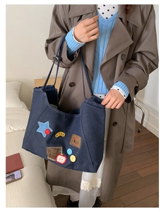 Detail of vintage denim tote bag featuring colorful star patches and letter embroidery