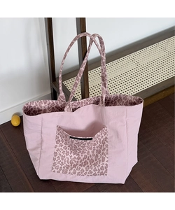 Detail of pink canvas tote bag showing leopard print lining and front pocket on wood floor