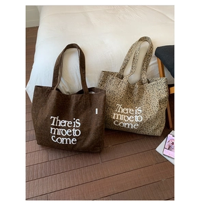 Detail view of large canvas tote bags in leopard print and brown with slogan print