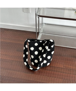 Detailed texture of black plush bucket bag featuring white polka dot patterns