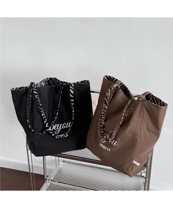 Detail of nylon tote bags with zebra print handles and embroidered typography