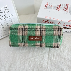 Close-up of green plaid fabric pencil case with leather logo and sturdy metal zipper