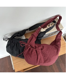 Detail of plaid canvas croissant bags with drawstring bow accents and zipper closure