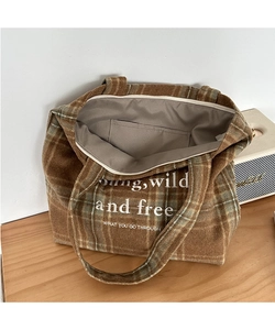 Close-up of brown plaid wool tote bag interior lining and white slogan embroidery