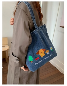 Detailed view of dark blue denim tote bag with embroidered puppies and nature park text