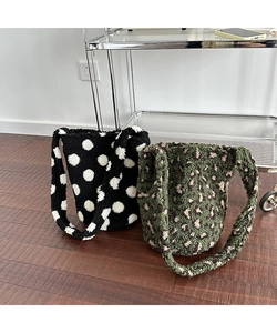 Detail showing plush bucket bags with polka dot and green leopard patterns on wood floor