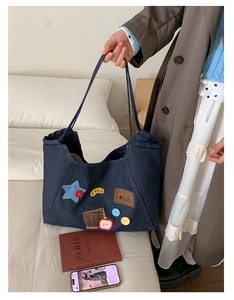 Detail of denim tote bag with colorful star and apple patches in a cozy home setting