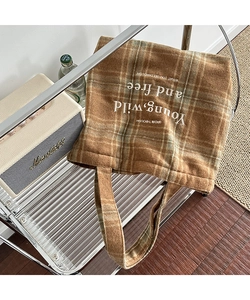 Detail view of plaid tote bag featuring embroidered Young Wild and Free lettering