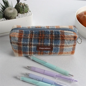 Detail of vintage wool plaid pencil case with brown leather tag and multi-color fabric
